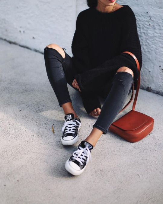 Andy Csinger wears black and white low-top converse with rolled distressed jeans, and a cosy black knitted sweater. Sweater: H&M, Jeans: Topshop, Shoes: Converse.